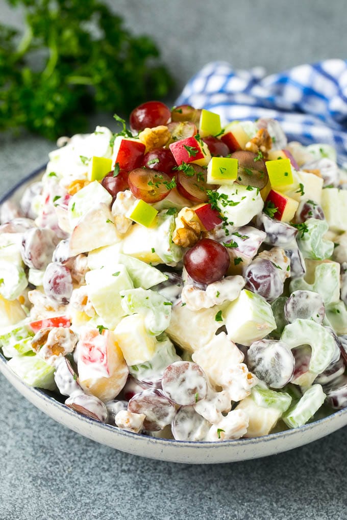 A bowl of Waldorf salad made with fruit, nuts and celery all tossed in a creamy dressing.