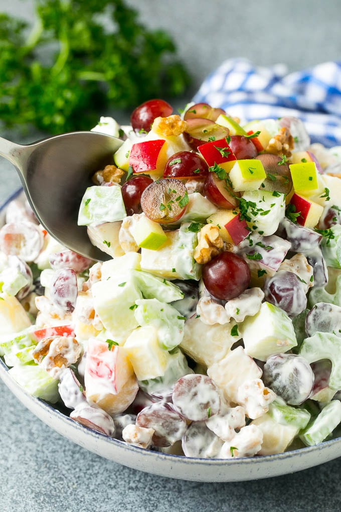 A serving spoon in a bowl of apple walnut Waldorf salad.