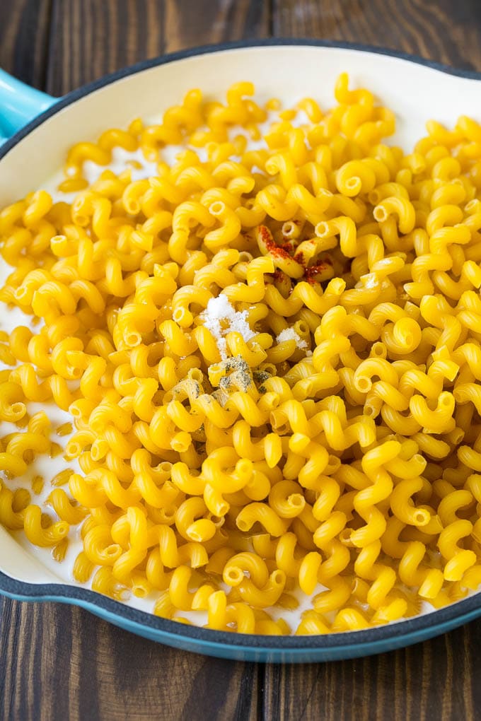 Uncooked pasta and spices with milk in a pan.