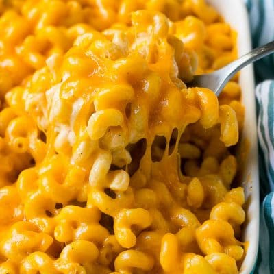 Baked mac and cheese with a serving spoon lifting up a portion.