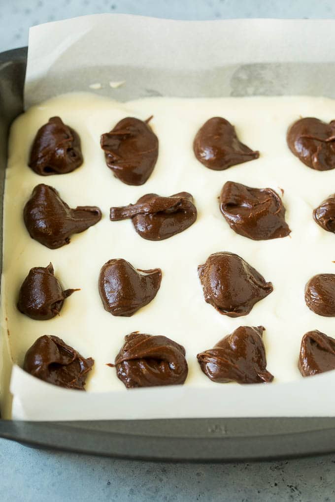 Brownies topped with a layer of cheesecake and dollops of chocolate batter.