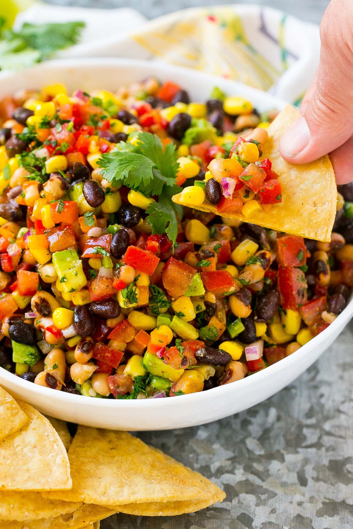 A hand scooping up Texas caviar on a chip.