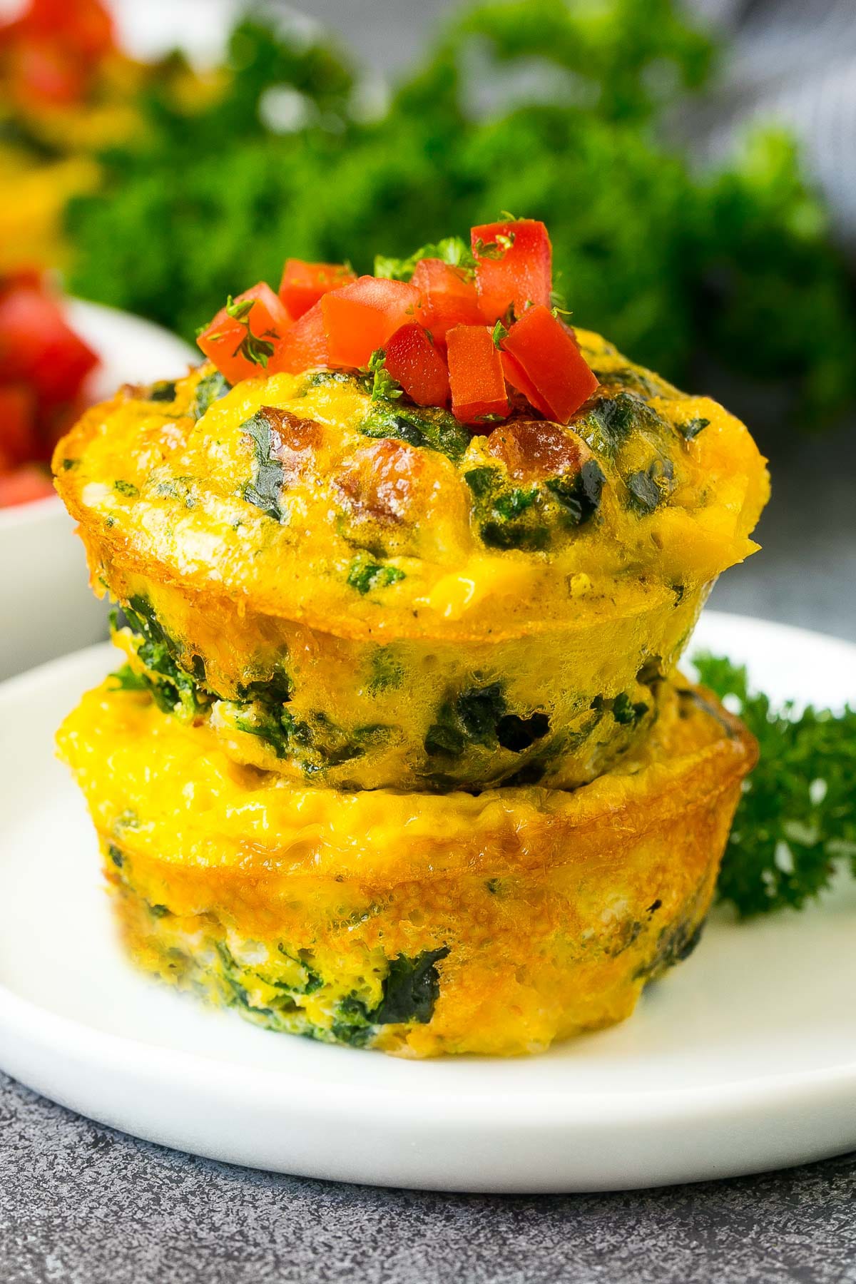 Two breakfast egg muffins stacked on a plate.