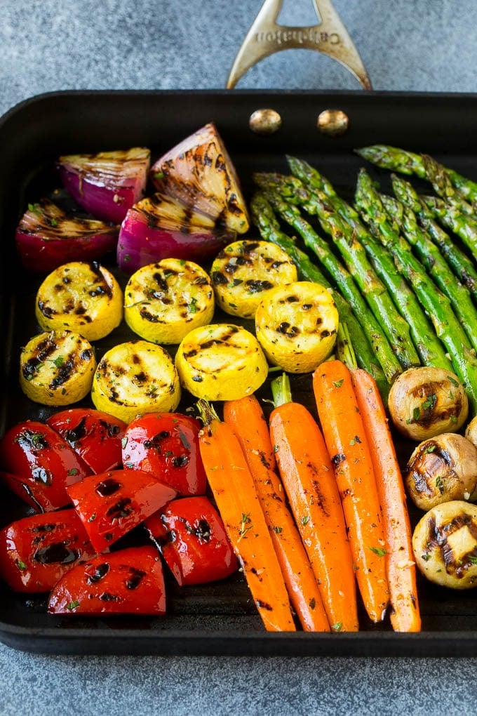 A grill pan with an assortment of vegetables cooking on it.