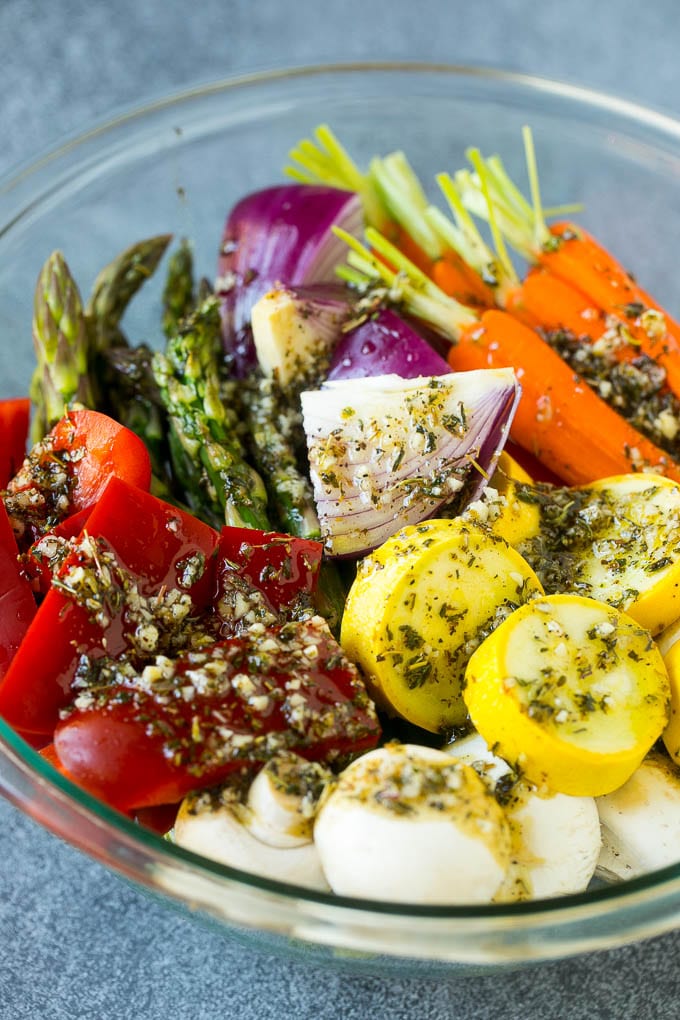 Raw vegetables in a bowl with garlic, herbs and olive oil.