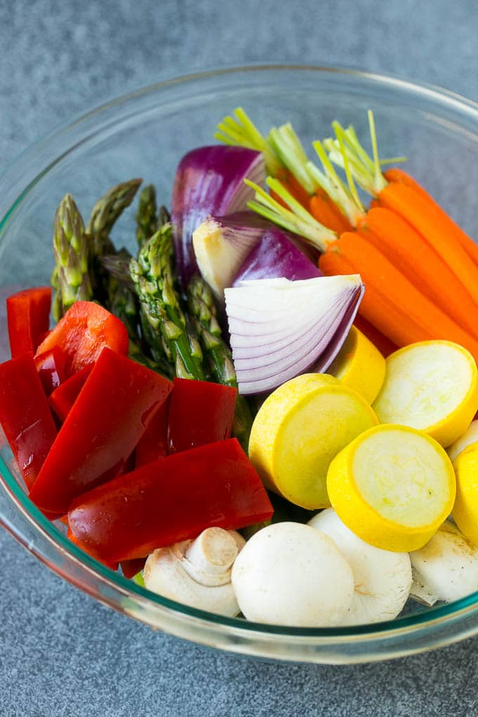 Carrots, peppers, squash, mushrooms and asparagus in a mixing bowl.