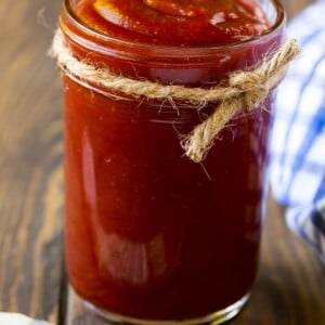 A jar of homemade BBQ sauce with a basting brush next to it.