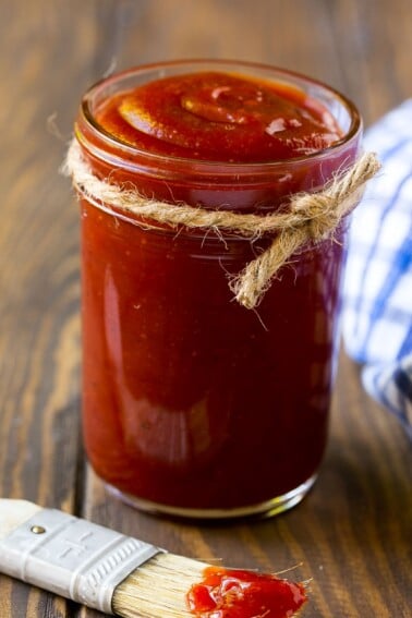 A jar of homemade BBQ sauce with a basting brush next to it.