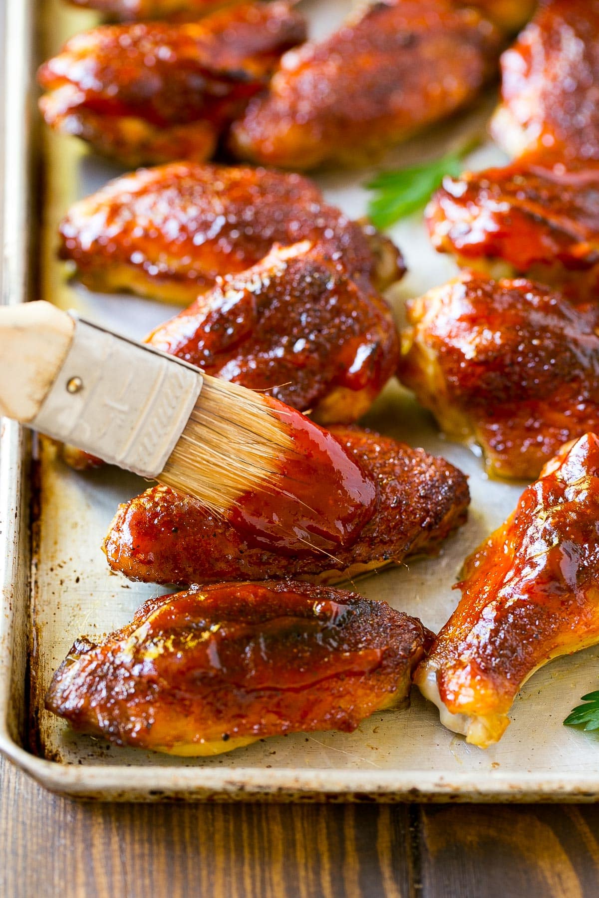 Homemade BBQ sauce being brushed onto chicken wings.