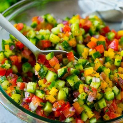 A bowl of Israeli salad with a serving spoon in it.