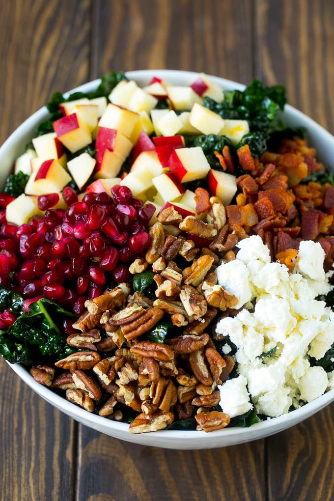 Kale salad topped with apples, bacon, pecans, pomegranate and feta cheese.