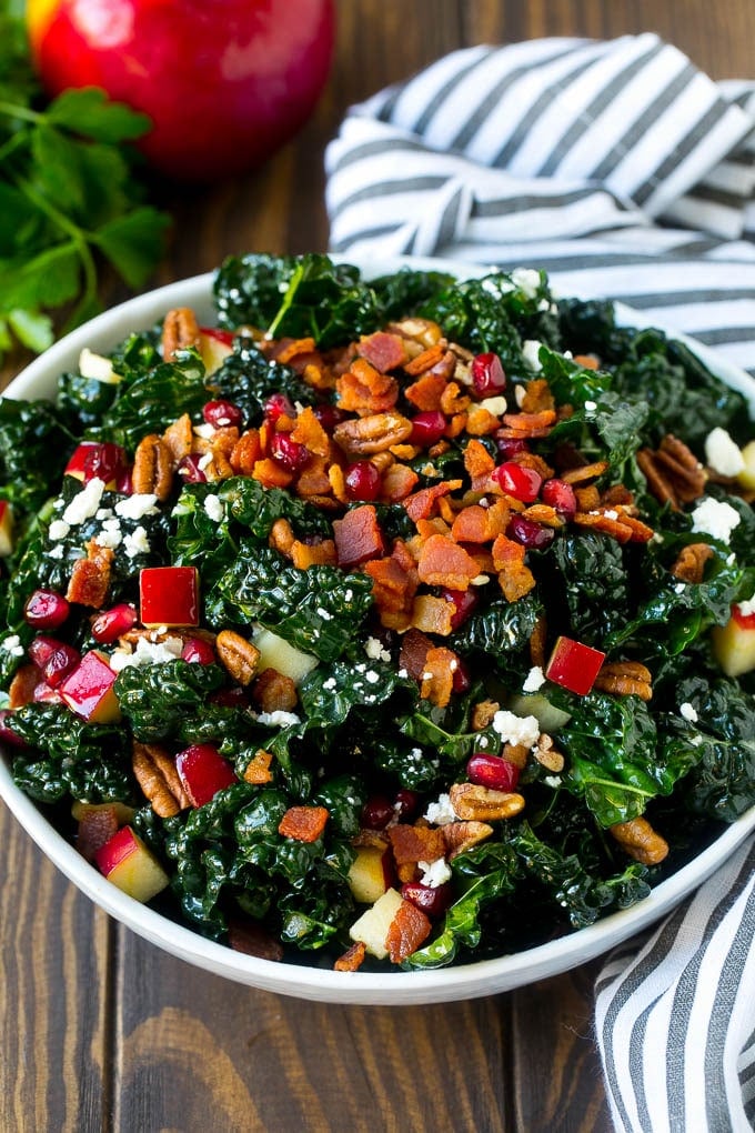 A bowl of tuscan kale salad garnished with cooked bacon.