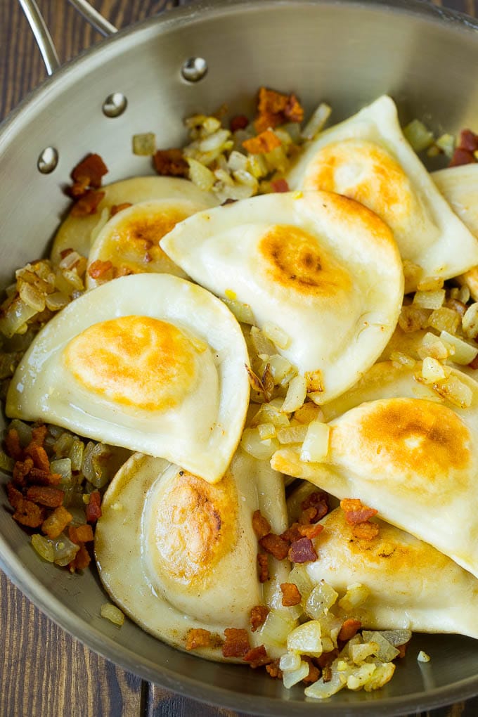 Sauteed pierogis with bacon and onions in a skillet.