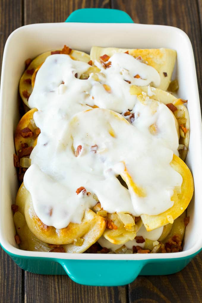 Pierogies in a casserole dish covered with creamy sauce.