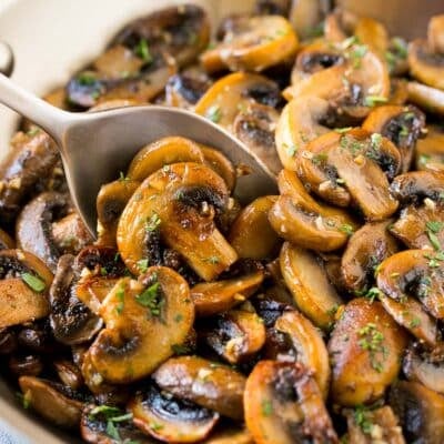 A pan of sauteed mushrooms with a serving spoon in it.