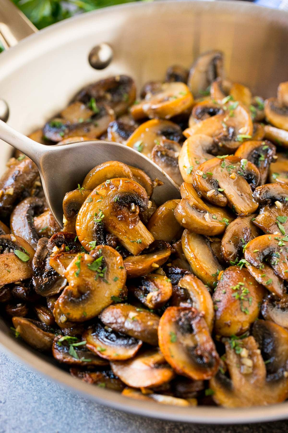 A pan of sauteed mushrooms with a serving spoon in it.