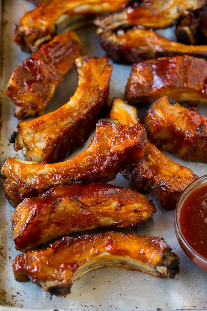 Slow cooker ribs coated in BBQ sauce on a sheet pan.