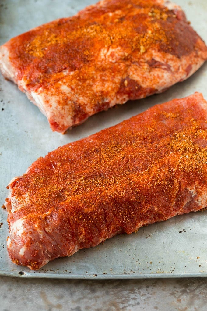 Slabs of uncooked ribs coated in BBQ spice rub.