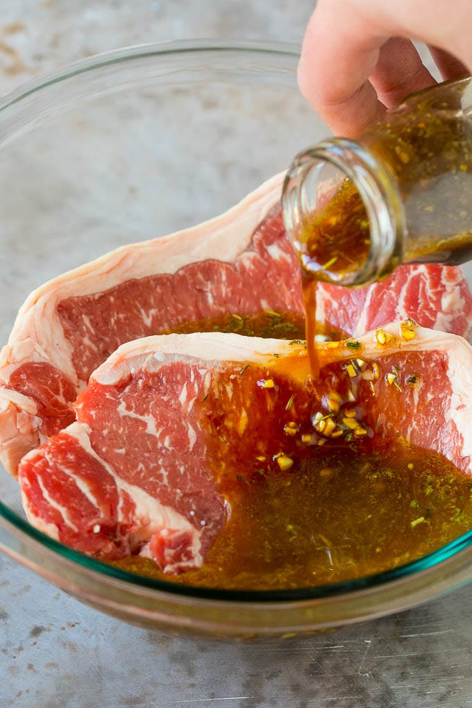 Marinade being poured into a bowl of steaks.