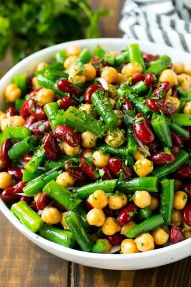 A serving bowl of three bean salad topped with parsley.