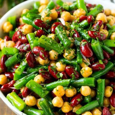 A serving bowl of three bean salad topped with parsley.