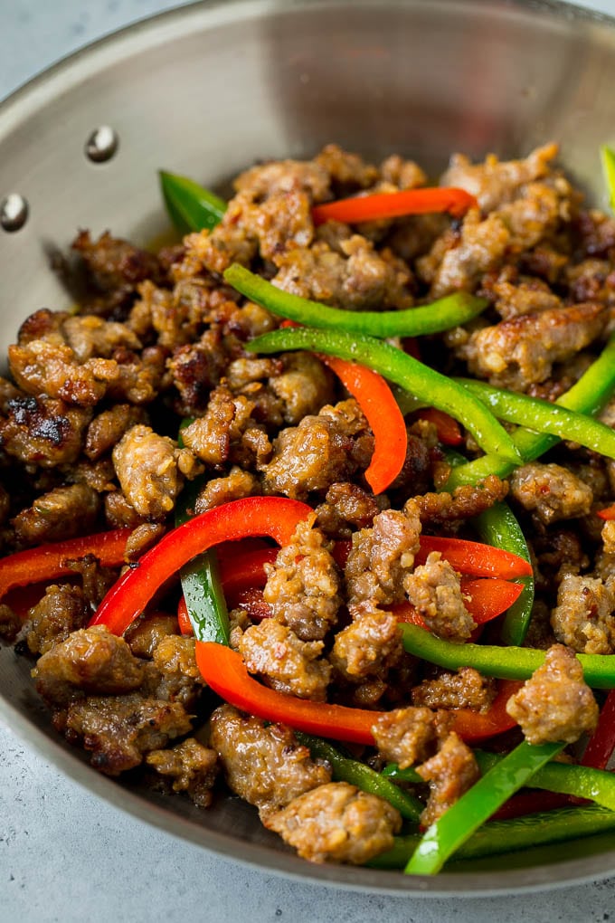 Cooked Italian sausage and peppers in a skillet.