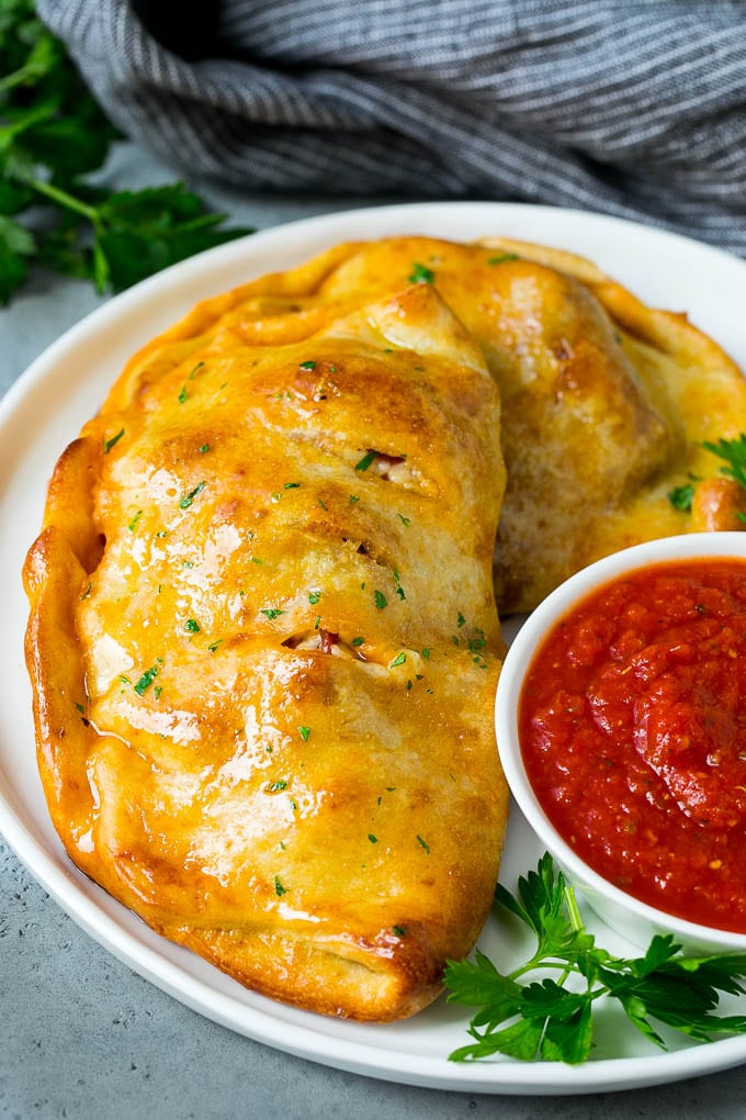 A homemade calzone served with pizza sauce.