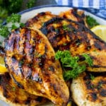 The best chicken marinade covering grilled chicken breasts, garnished with lemon.