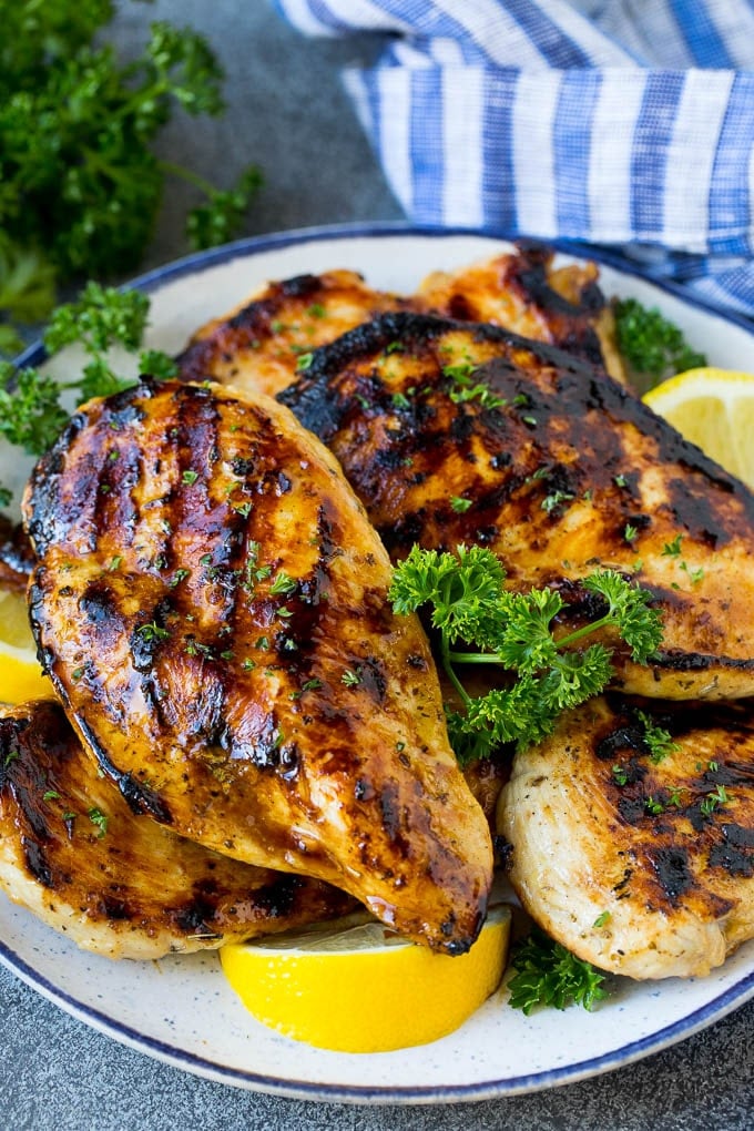 The best chicken marinade covering grilled chicken breasts, garnished with lemon.