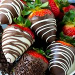 A plate of chocolate covered strawberries dipped in white and dark chocolate.