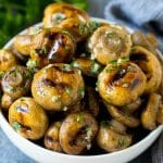 Grilled mushrooms coated with garlic butter in a serving bowl.