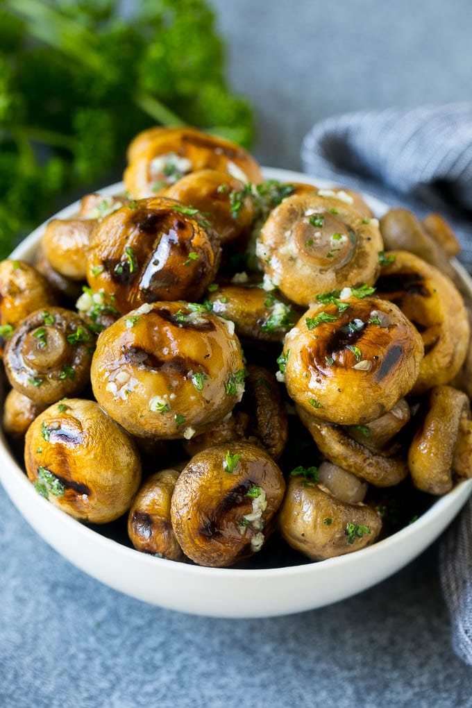 Grilled mushrooms coated with garlic butter in a serving bowl.