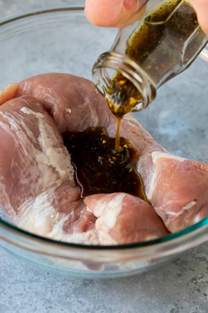 Marinade being poured over pork tenderloin.