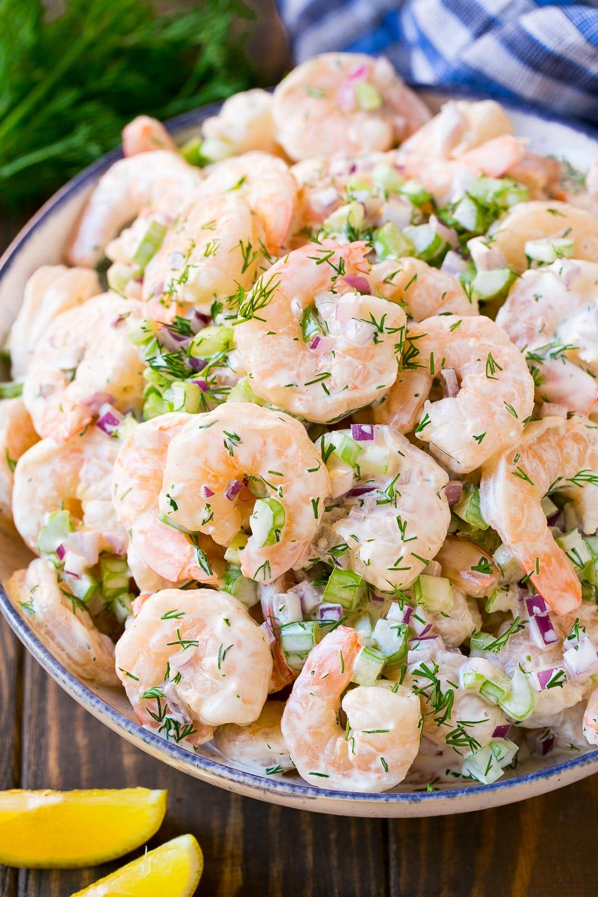 A bowl of shrimp salad with celery and dill, garnished with lemon.