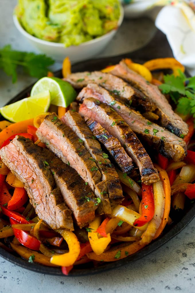 A skillet of steak fajitas with red and yellow peppers.