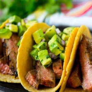 Steak tacos topped with avocado, red onion and cilantro.