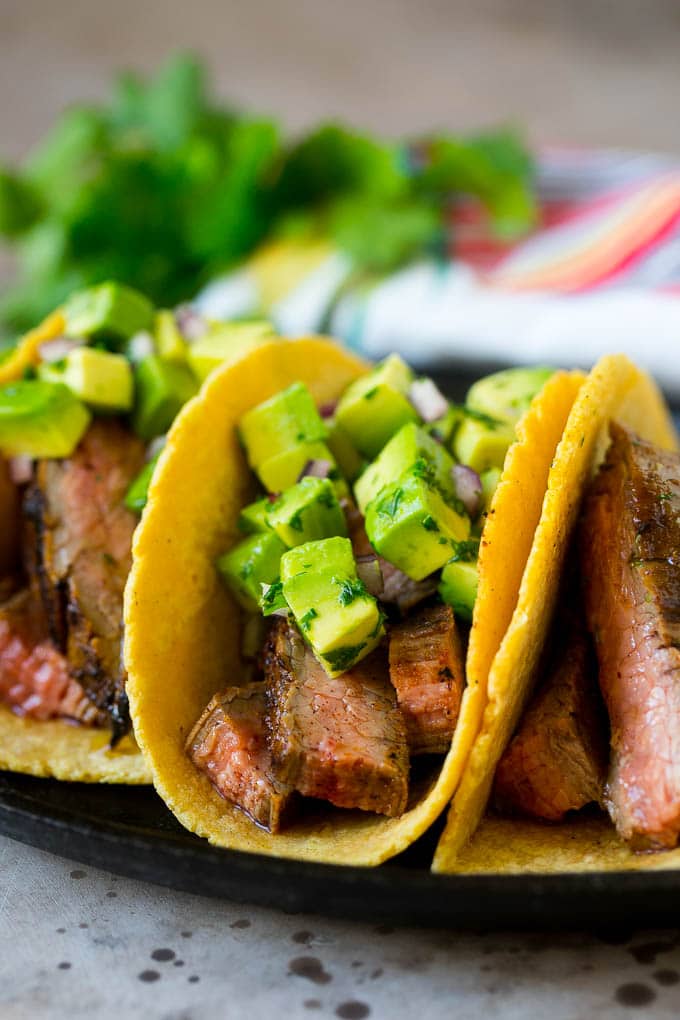 Steak tacos topped with avocado, red onion and cilantro.