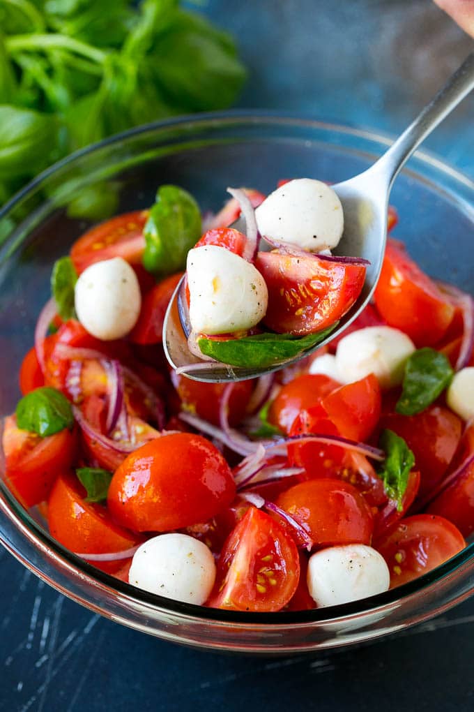 A serving spoon holding a portion of fresh tomato salad.