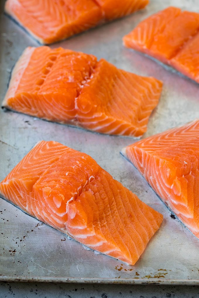 Raw salmon fillets on a sheet pan.