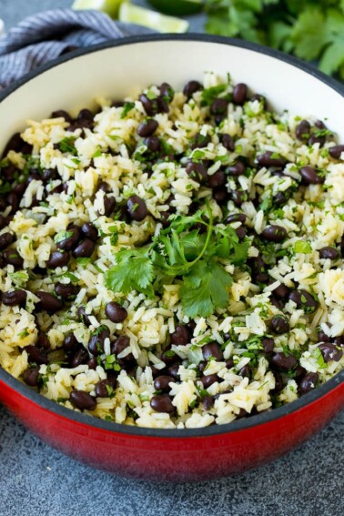 Black beans and rice in a pot topped with cilantro sprigs.