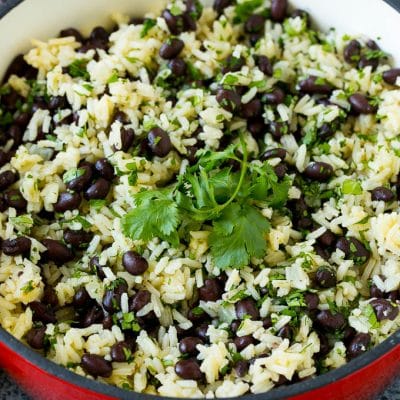 Black beans and rice in a pot topped with cilantro sprigs.