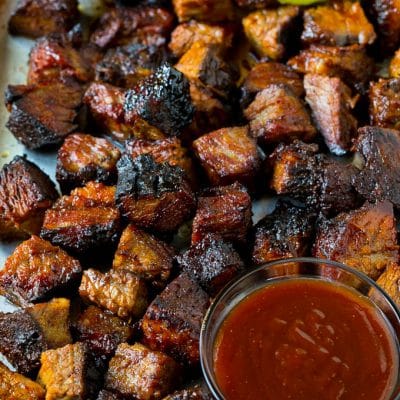 Burnt ends on a sheet pan served with BBQ sauce, red onions and pickles.