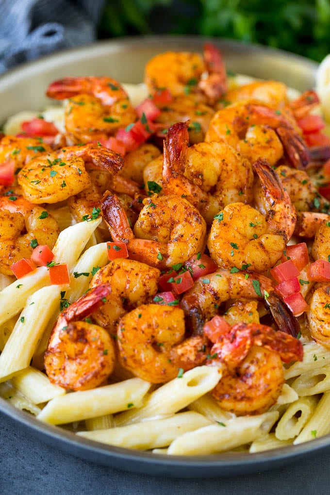A pan of Cajun shrimp pasta garnished with tomatoes and herbs.