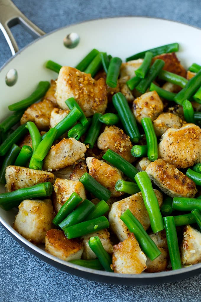 Cooked chicken and green beans in a pan.