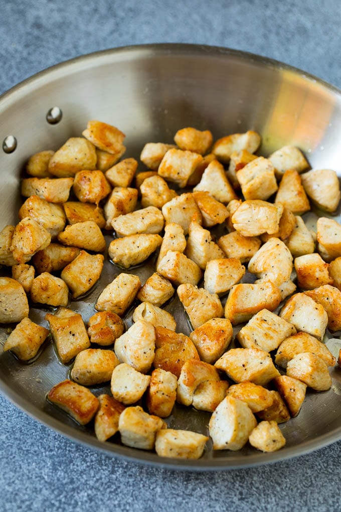 Cooked chicken pieces in a metal pan.