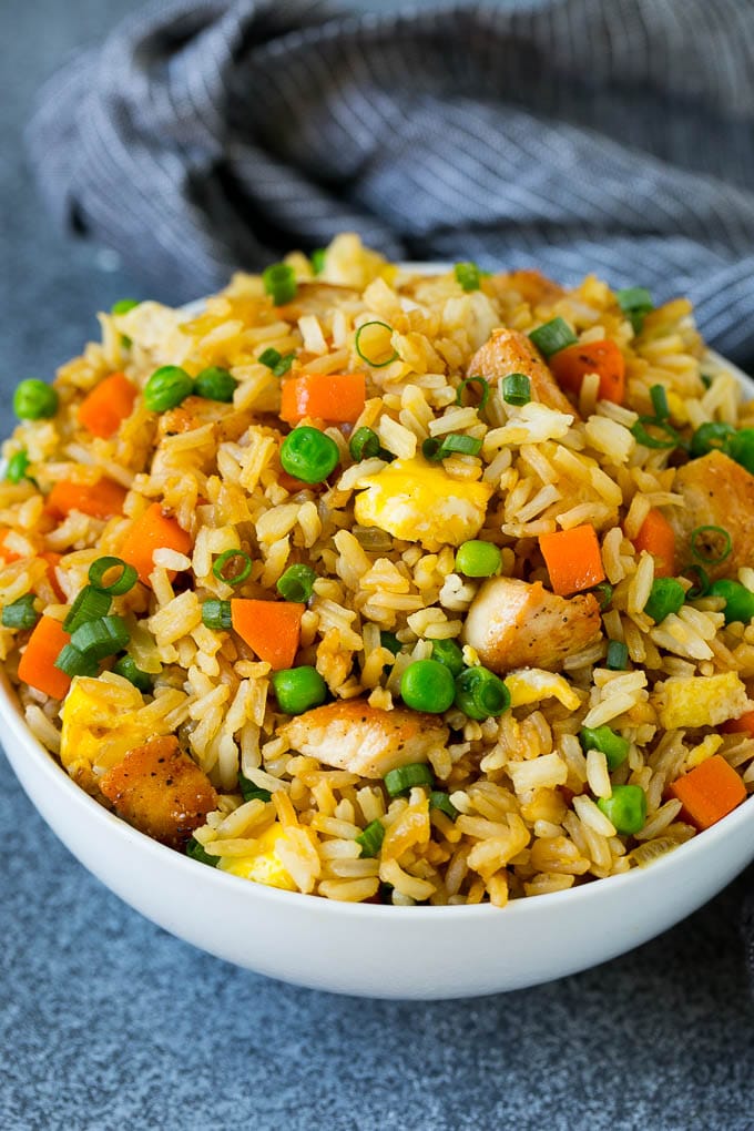 A bowl of chicken fried rice topped with sliced green onions.