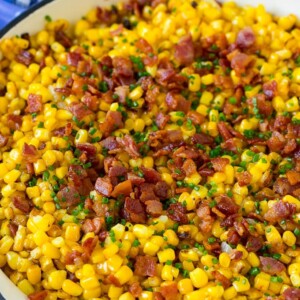 Fried corn topped with bacon and chives in a pan.
