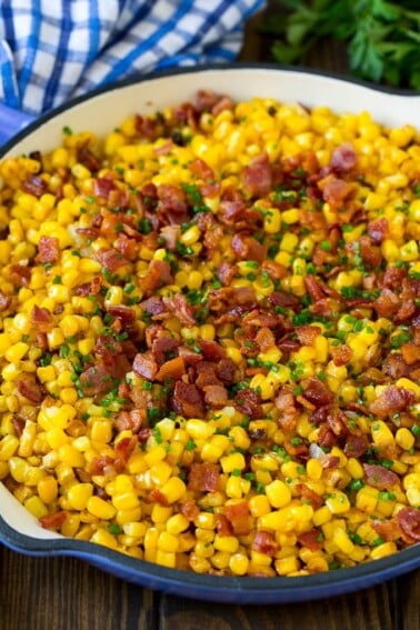 Fried corn topped with bacon and chives in a pan.