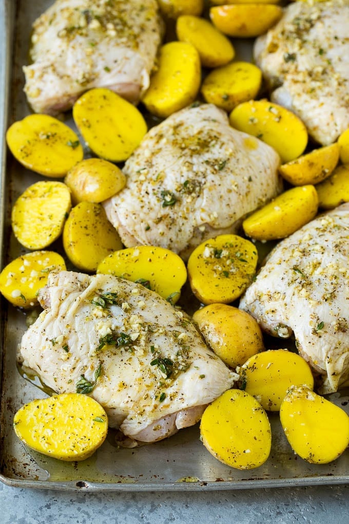 Chicken thighs and potatoes spread out on a sheet pan.