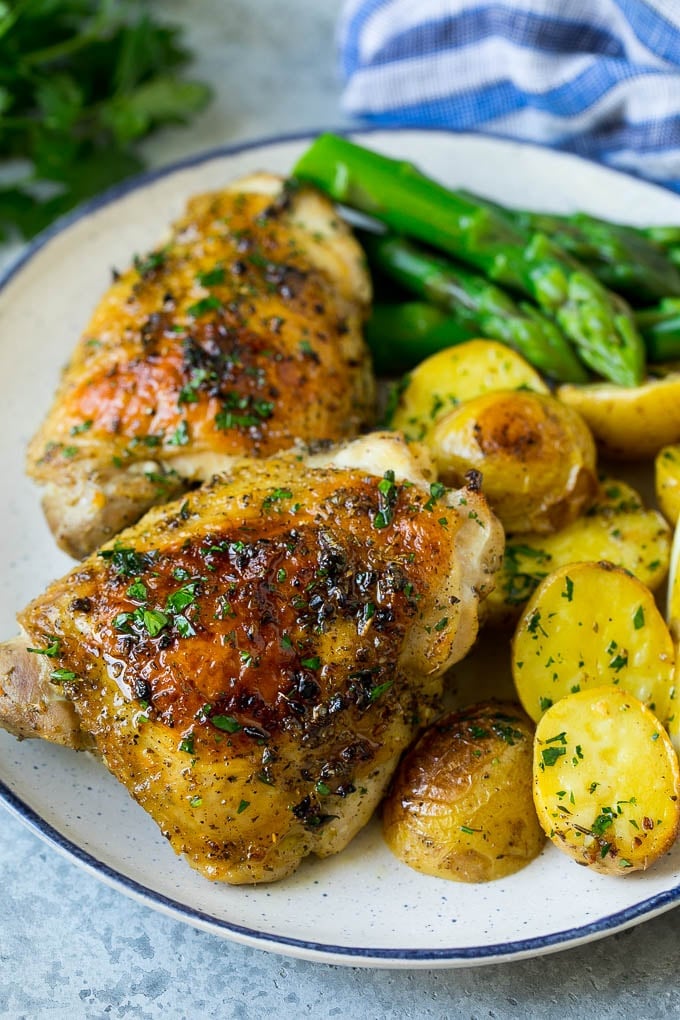 Greek chicken and potatoes on a plate with asparagus.